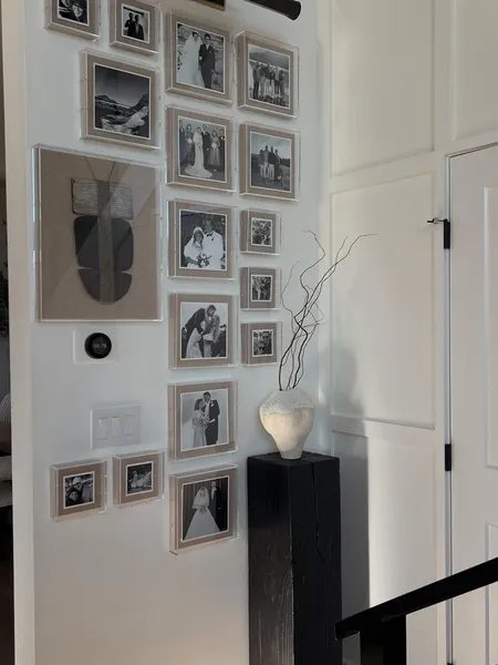 Black pedestal beside a gallery wall of framed family photos
