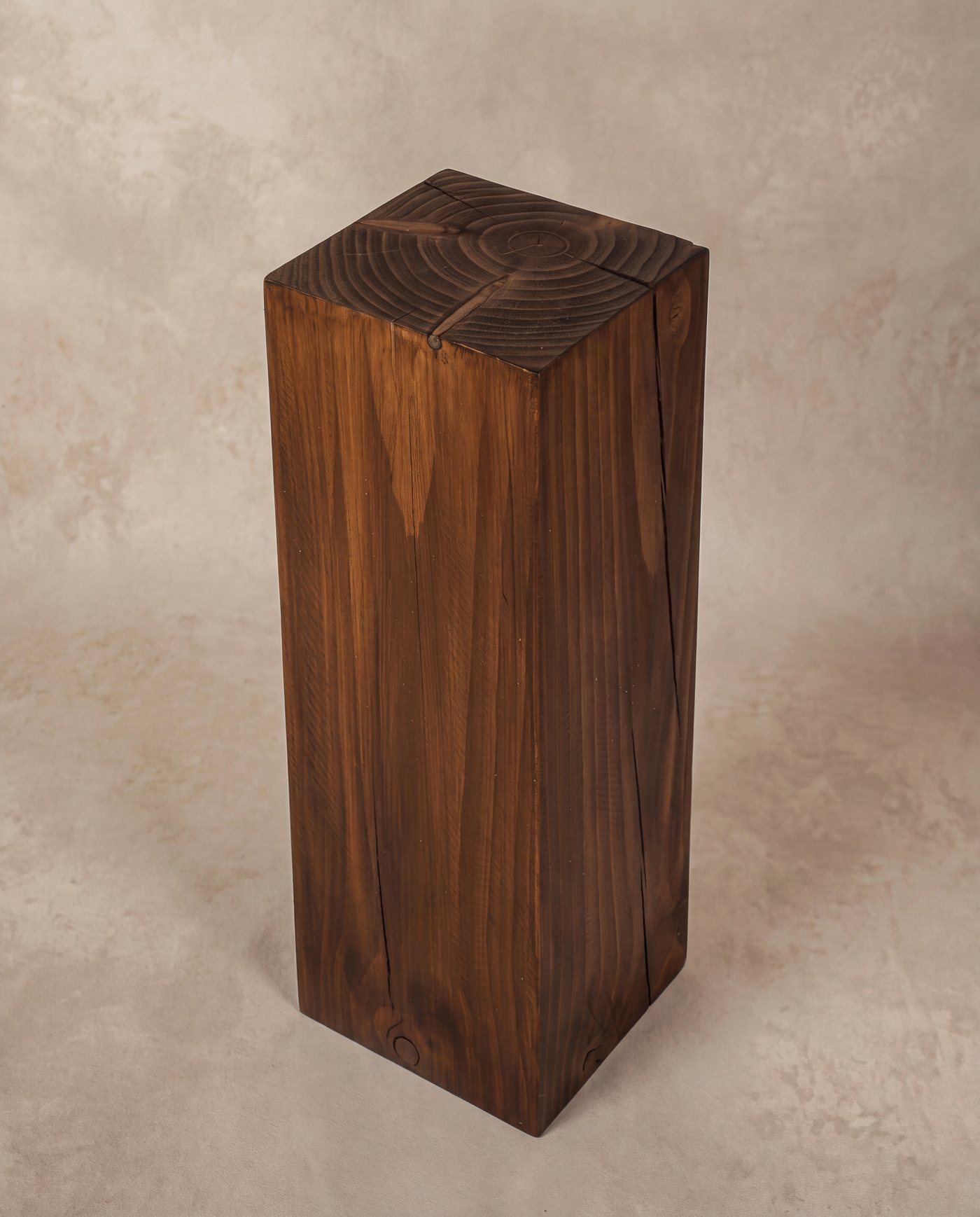 Walnut pedestal against a plaster backdrop