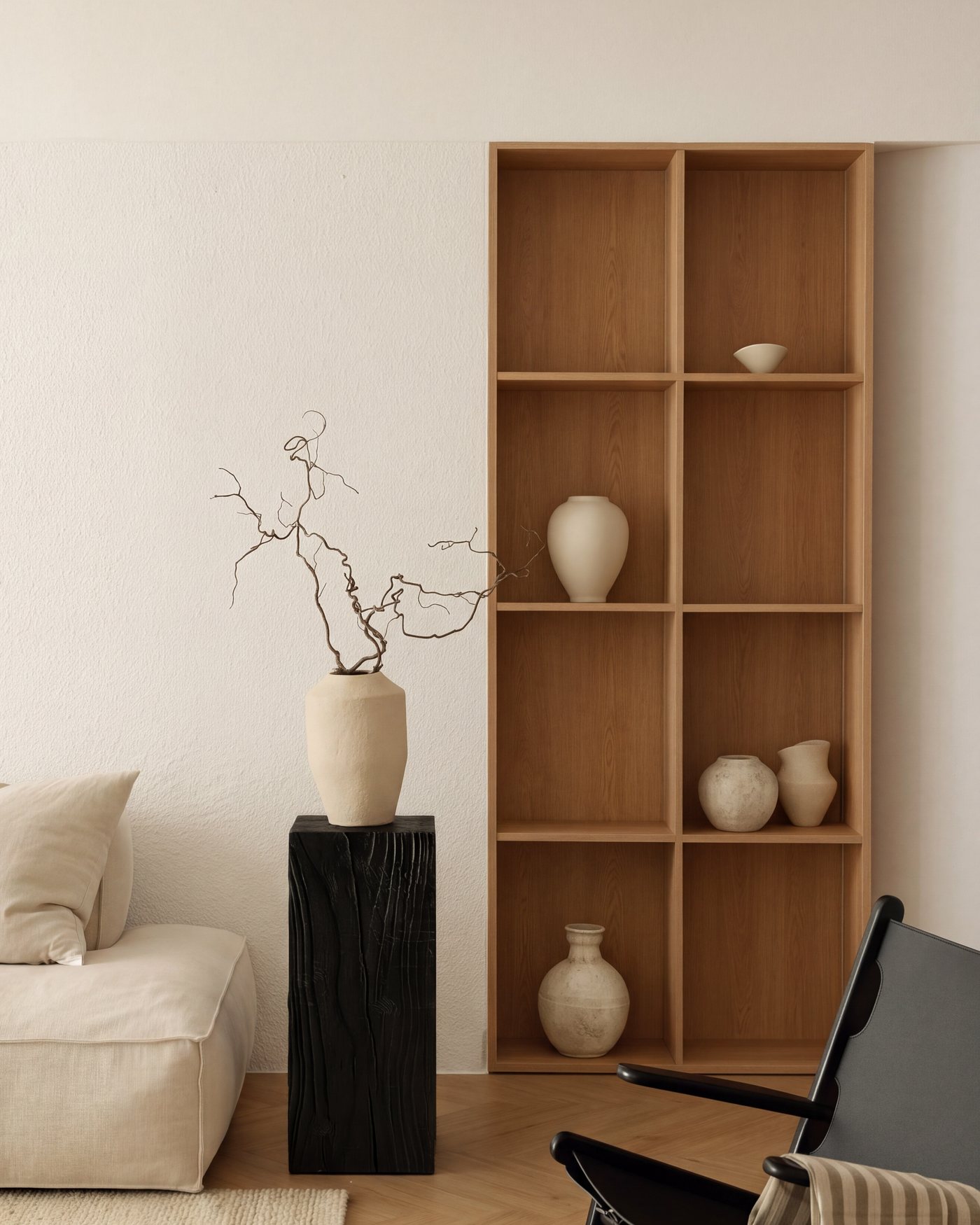 Black pedestal with a clay vase and branches beside an oak shelf